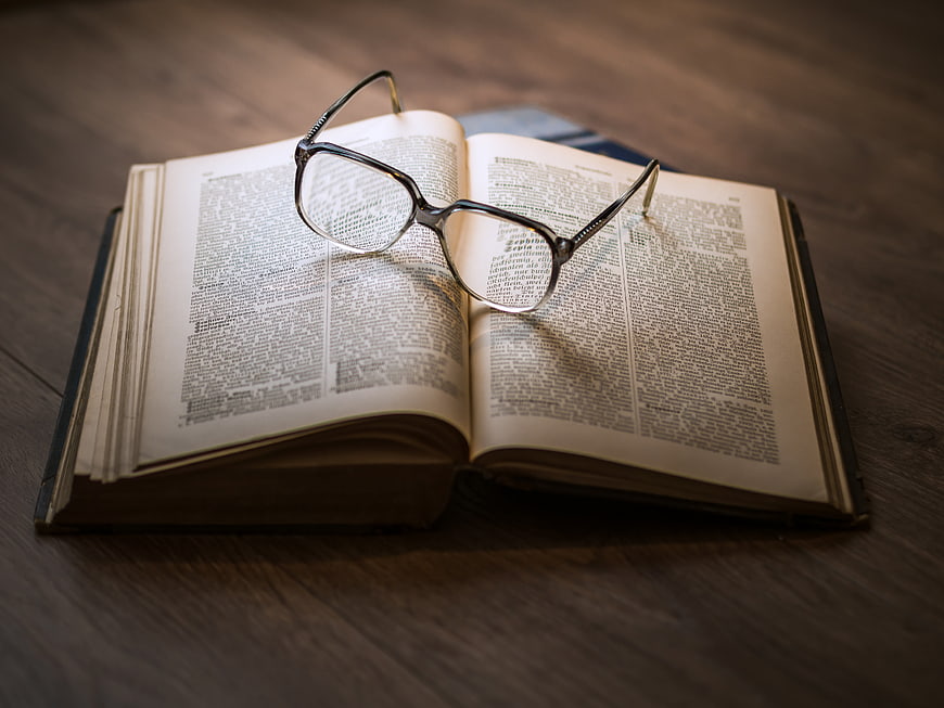 Vintage eyeglasses resting on an open book on a wooden table