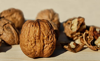 Close-up of whole and cracked walnuts on a wooden surface