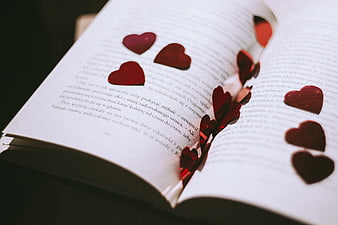 Red glitter hearts scattered on open book pages