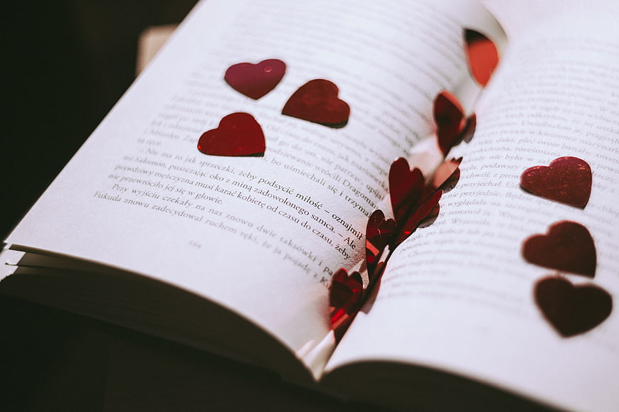 Red glitter hearts scattered on open book pages