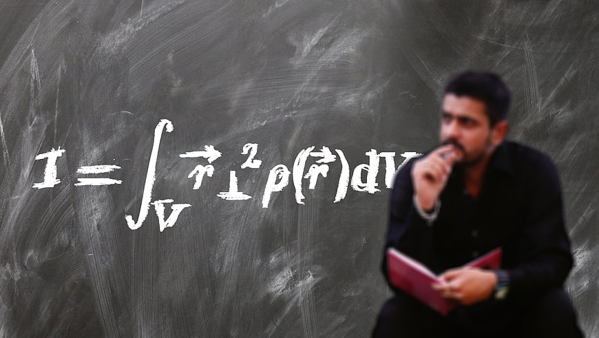 Professor thinking about physics formula on chalkboard