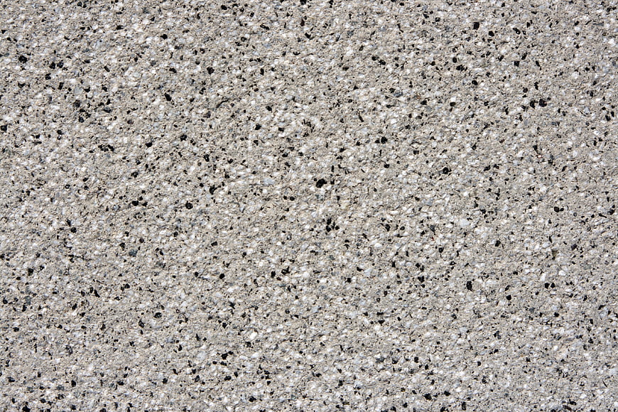 Close-up texture of gray concrete surface with black and white aggregate speckles