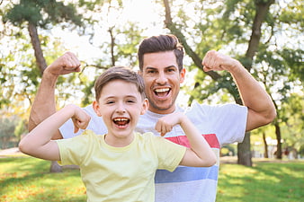 Happy Father and Son Flexing Muscles in Park