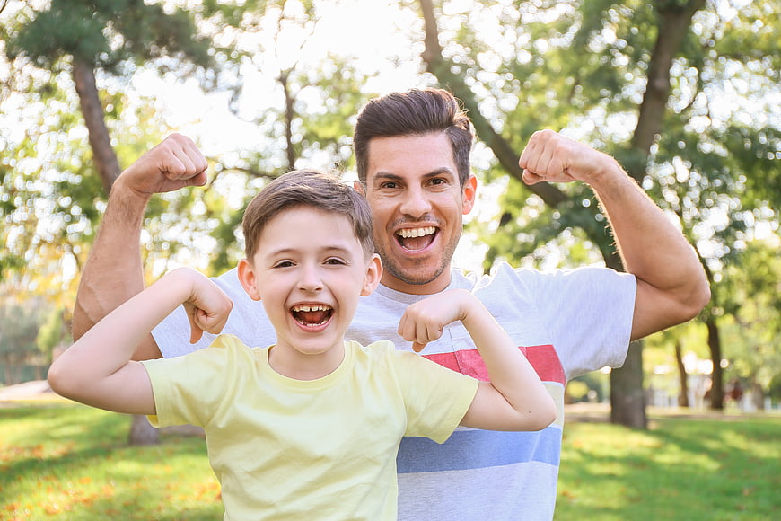 Happy Father and Son Flexing Muscles in Park