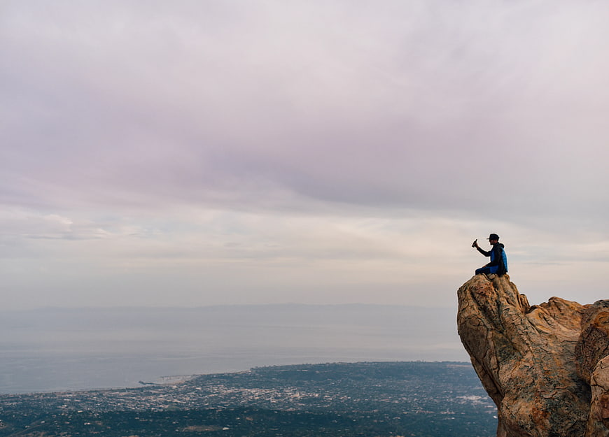 Man Taking Selfie on Rocky Mountain Peak Overlooking City