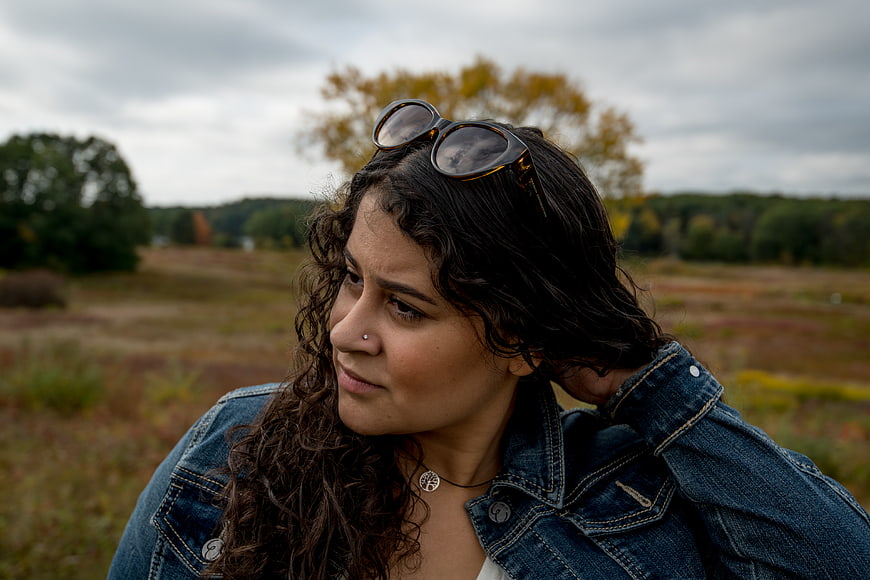 Young Woman with Curly Hair in Denim Jacket Outdoors