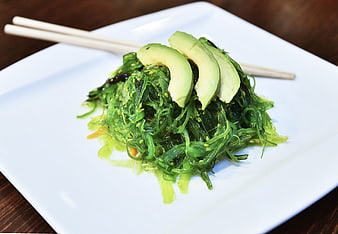Wakame seaweed salad with avocado slices on white plate