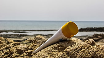 Sunscreen tube on rocky beach with ocean background
