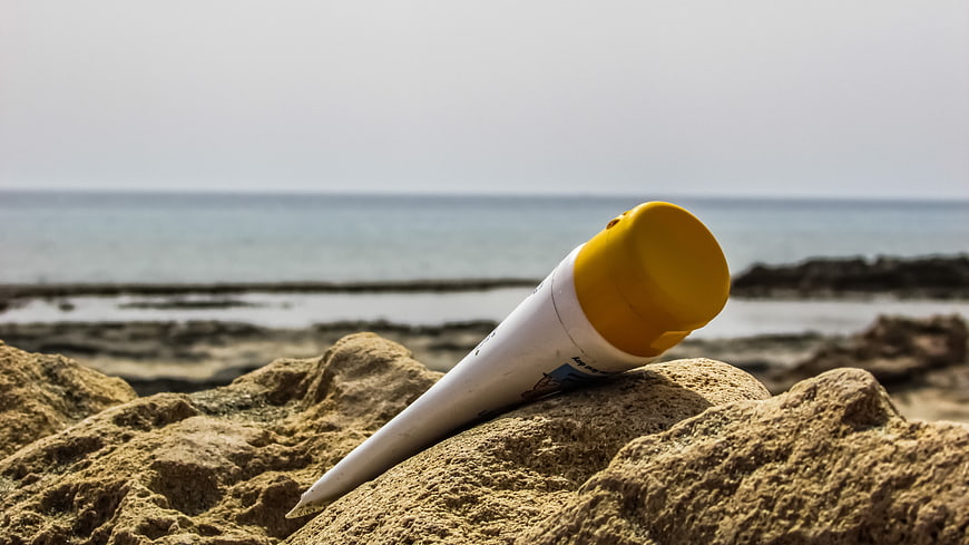 Sunscreen tube on rocky beach with ocean background