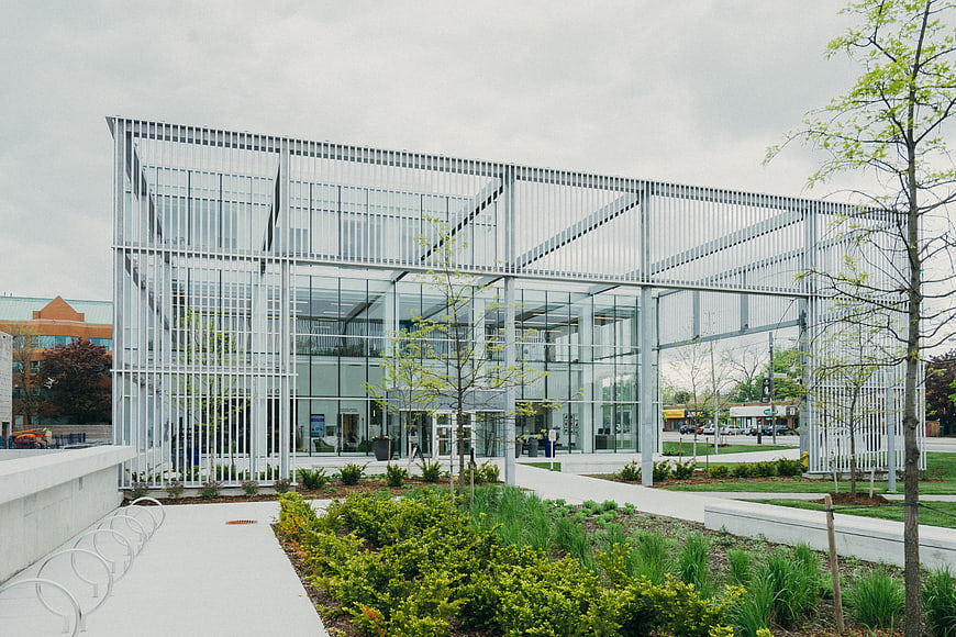 Modern glass building with metal framework and green landscaping