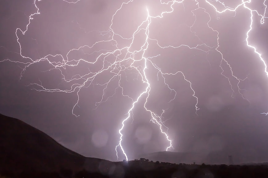 Dramatic Lightning Storm Over Dark Mountain Silhouette