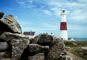 Portland Bill Lighthouse on Rocky Coastline with Blue Sky