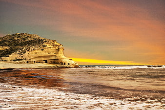 Coastal cliff with sea caves at sunset