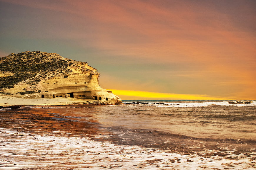 Coastal cliff with sea caves at sunset
