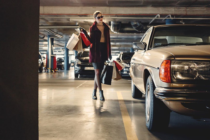 Stylish Woman with Shopping Bags Walking in Parking Garage