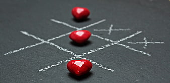 Red hearts winning tic-tac-toe game on chalkboard