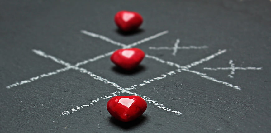 Red hearts winning tic-tac-toe game on chalkboard