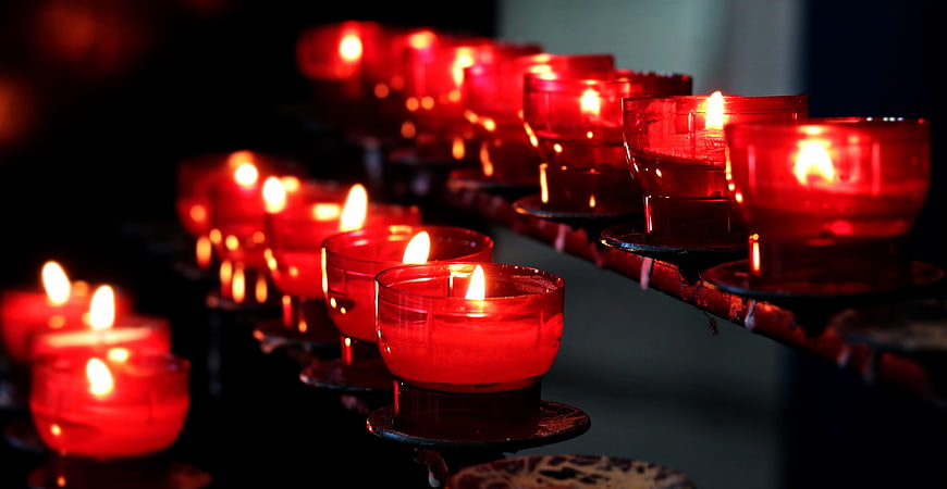 Rows of red votive candles burning in a church