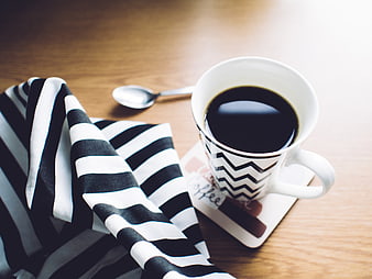 Black and white striped napkin with coffee cup on wooden table
