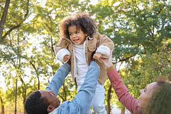 Happy family playing in park lifting child up