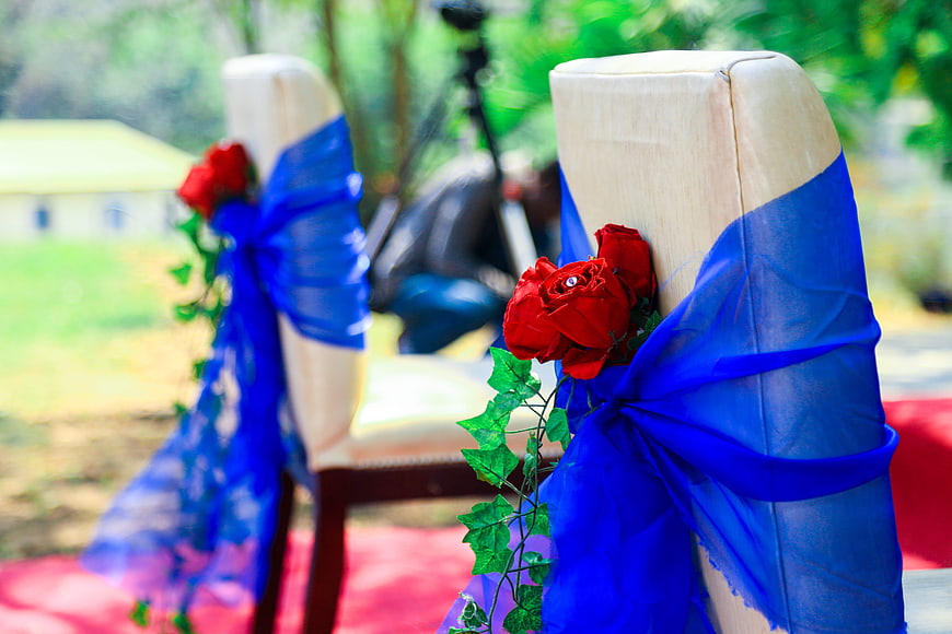 Decorated Wedding Chairs with Blue Sashes and Red Roses