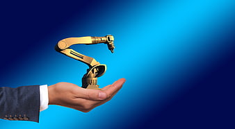 Businessman hand holding miniature golden robotic arm on blue background