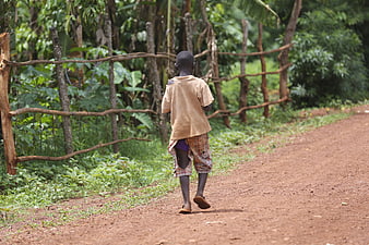 Young African boy walking away on a rural dirt road