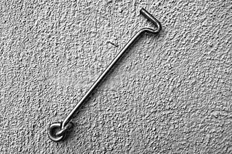 Black and white metal door hook on textured wall