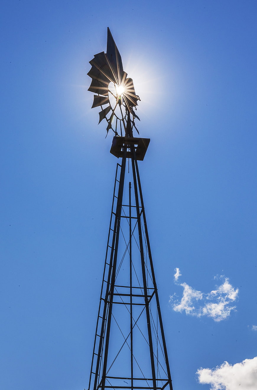 Silhouette of vintage windmill against blue sky with sunburst