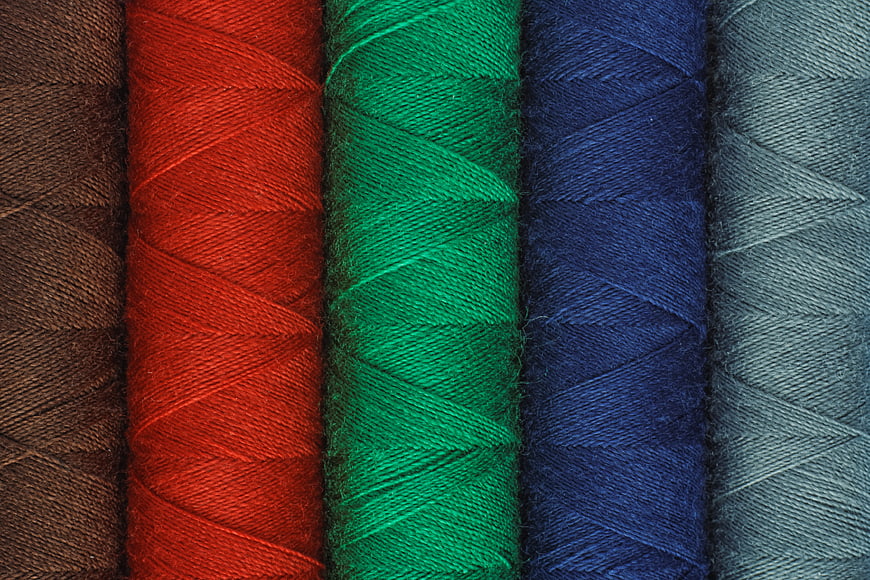 Close-up of colorful sewing threads in brown, red, green, blue, and gray