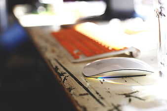 White Wireless Mouse on Rustic Wooden Desk with Orange Keyboard