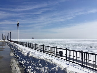 Snowy winter boardwalk with frozen lake and lighthouse