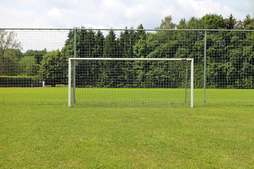 Empty Soccer Goal On Green Grass Field With Trees