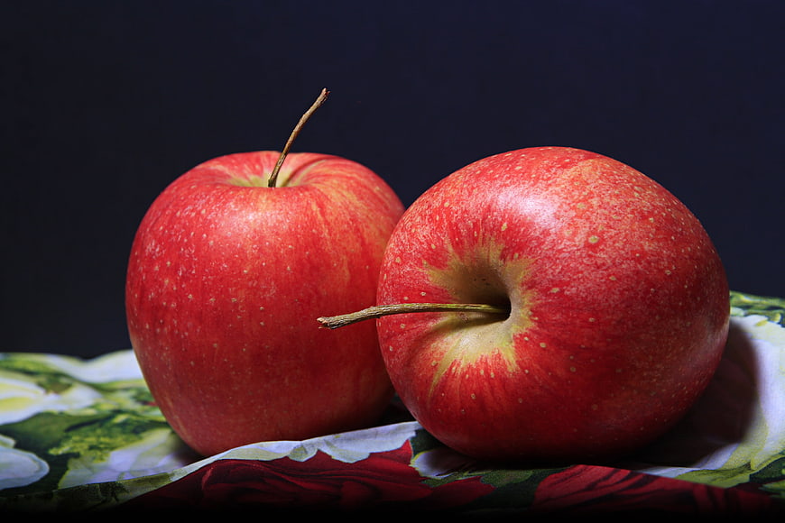 Two Fresh Red Apples on Floral Fabric