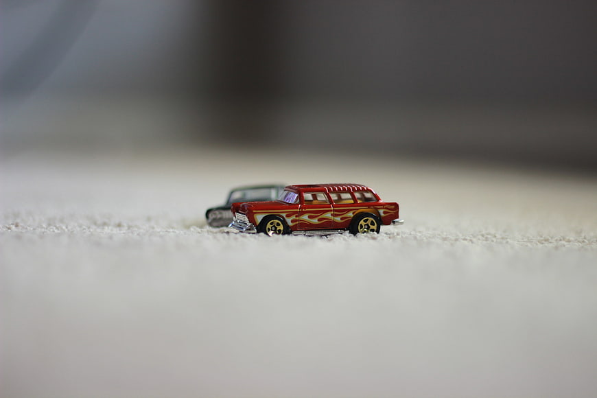 Red vintage toy car with flames on white carpet