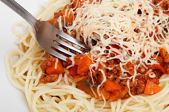 Close-up of spaghetti bolognese with melted cheese and fork
