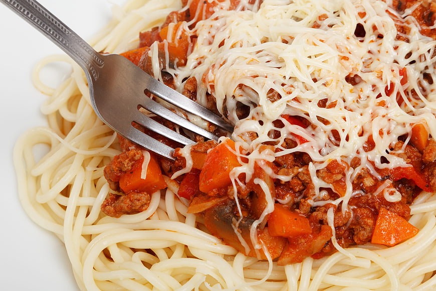 Close-up of spaghetti bolognese with melted cheese and fork