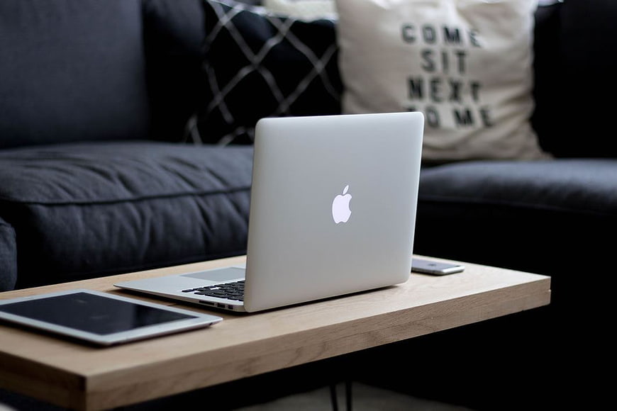 Laptop, tablet, and smartphone on wooden coffee table in living room