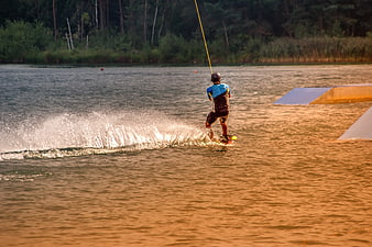 Wakeboarder performing a turn on a lake at golden hour