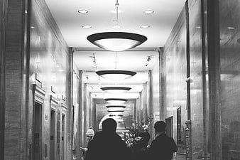 Black and white hotel hallway with elevators and people