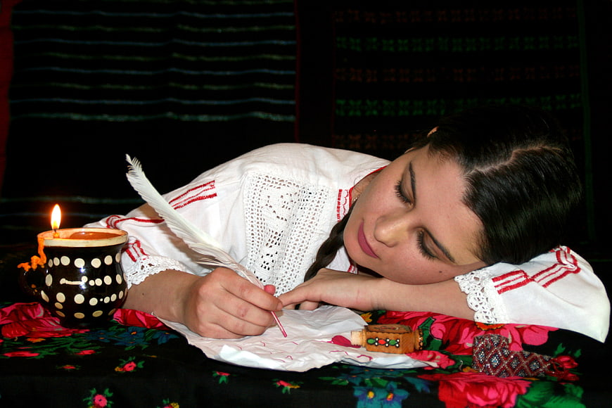 Woman in Traditional Embroidered Dress Writing by Candlelight