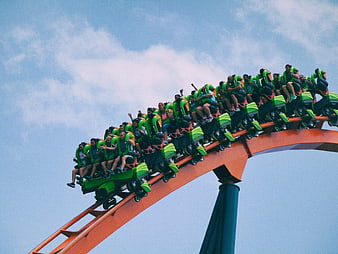Thrilling roller coaster ride with excited crowd against blue sky