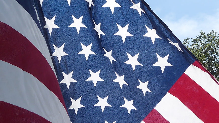 Close-up of waving American flag against blue sky