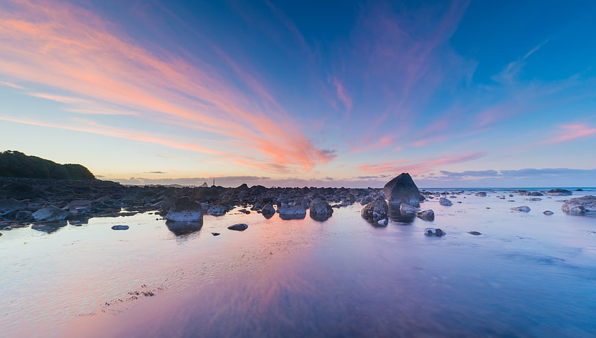 Dramatic Pink and Blue Sunset Sky Over Rocky Beach
