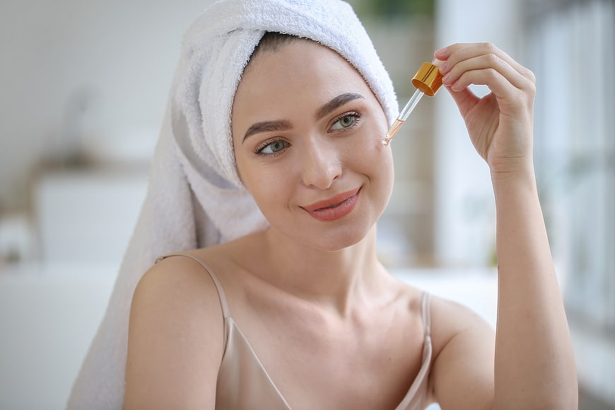 Woman applying serum with dropper for skincare routine