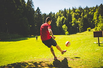 Man Kicking Soccer Ball on Grassy Field