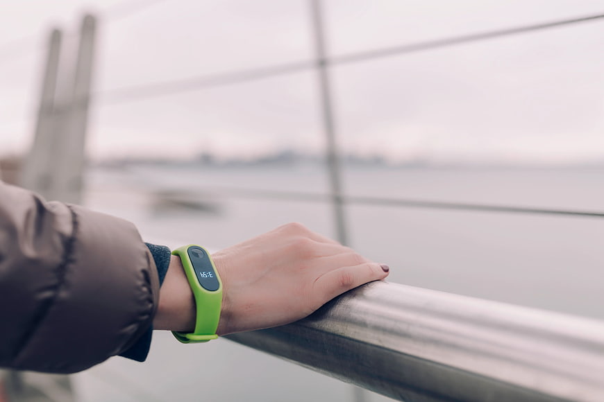 Close-up of hand with green fitness tracker on railing