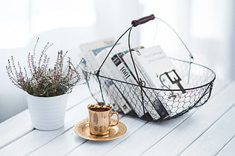 Cozy reading setup with golden cup and wire basket of books