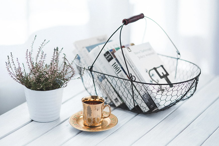 Cozy reading setup with golden cup and wire basket of books