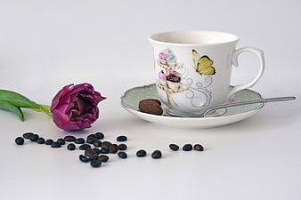 Decorative Coffee Cup with Tulip and Coffee Beans on White Background
